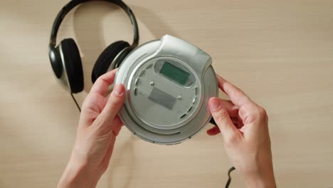 hands operating a portable cd player with headphones