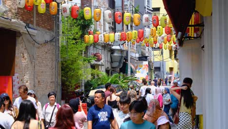 crowds of people in busy street of chinatown with chinese lanterns in capital city of kuala lumpur malaysia