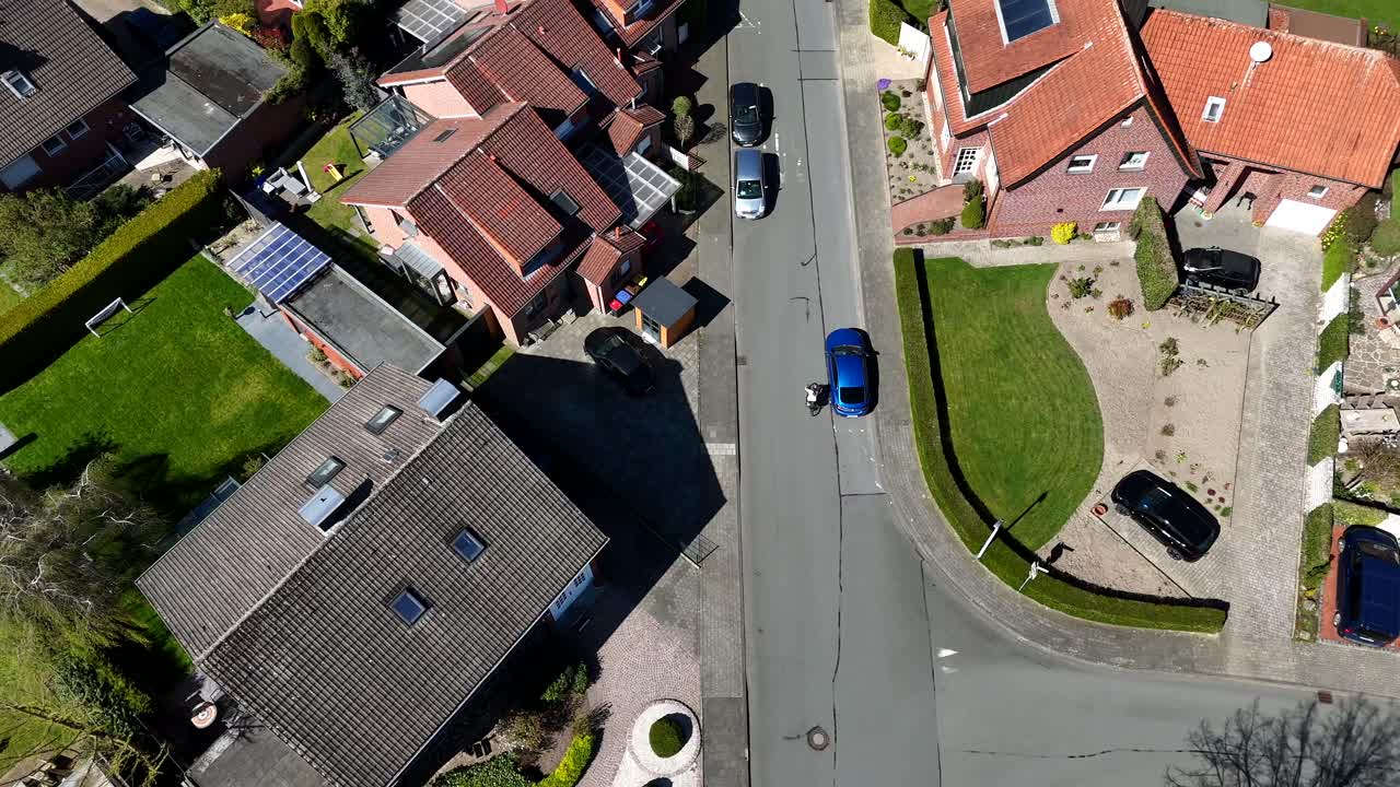 Aerial top down of person riding bike on street of neighborhood during sunny day. Peaceful small town in spring season. Housing area with single family houses.