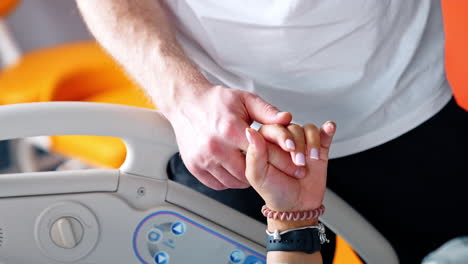 male hand holding female one. man comforts his wife lying in hospital bed. close up.