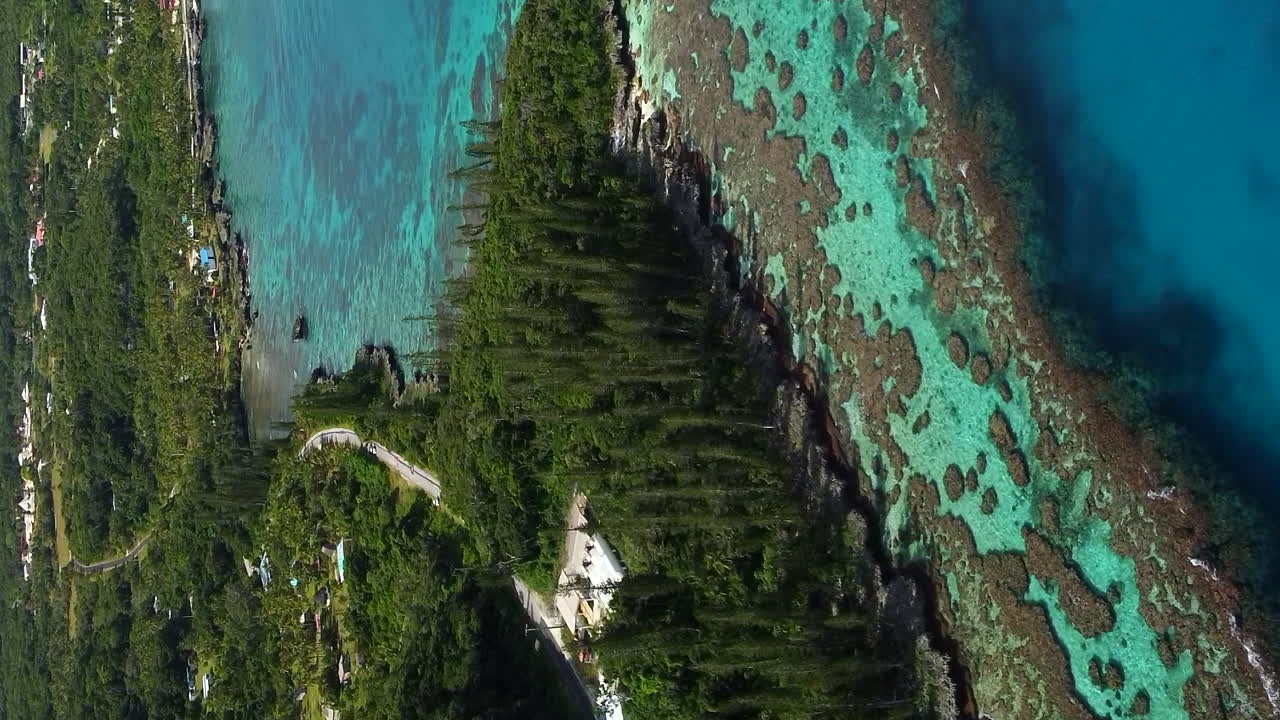 Aerial ascending shot revealing amazing coral bay beach and Tadine wharf, on Mar&eacute; Island, New Caledonia