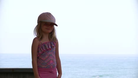 Retrato-De-Niña-Rubia-Con-Sombrero-Para-El-Sol-Y-Mar-De-Fondo