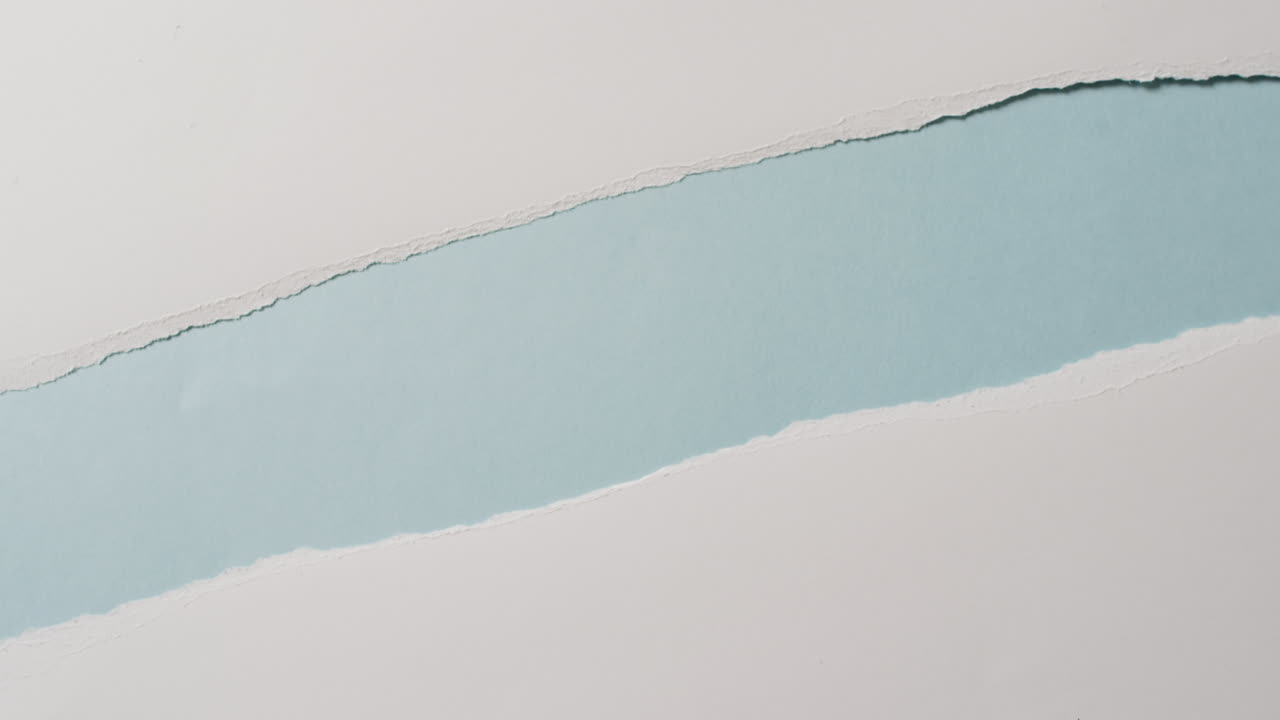 video de primer plano de pedazos rasgados de papel blanco sobre fondo azul
