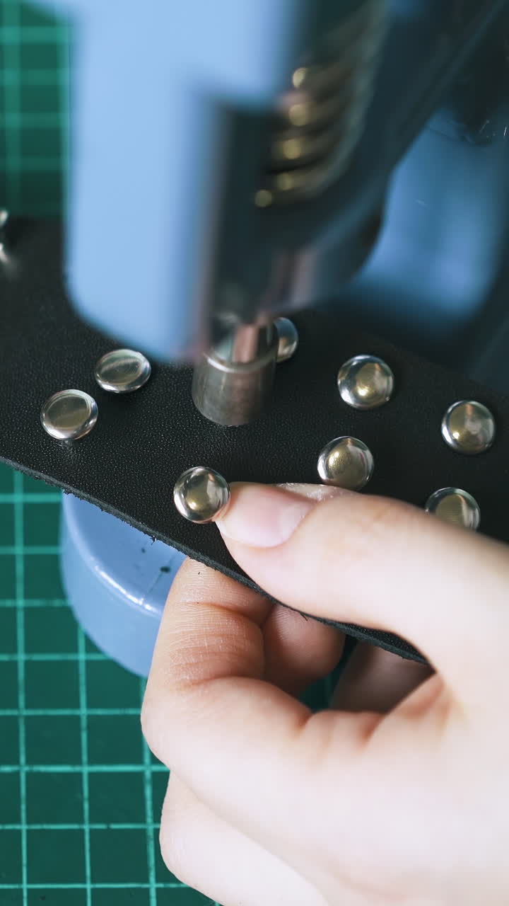 CU: Experienced worker sets metal holnitens in black choker with press machine on cutting board close view