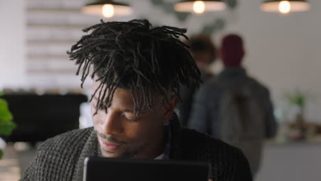 Joven-Afroamericano-Usando-Una-Tableta-Digital-En-Una-Cafetería-Bebiendo-Café-Disfrutando-Viendo-Entretenimiento-En-Línea-Leyendo-Redes-Sociales-En-Un-Dispositivo-Móvil-Sonriendo-Feliz