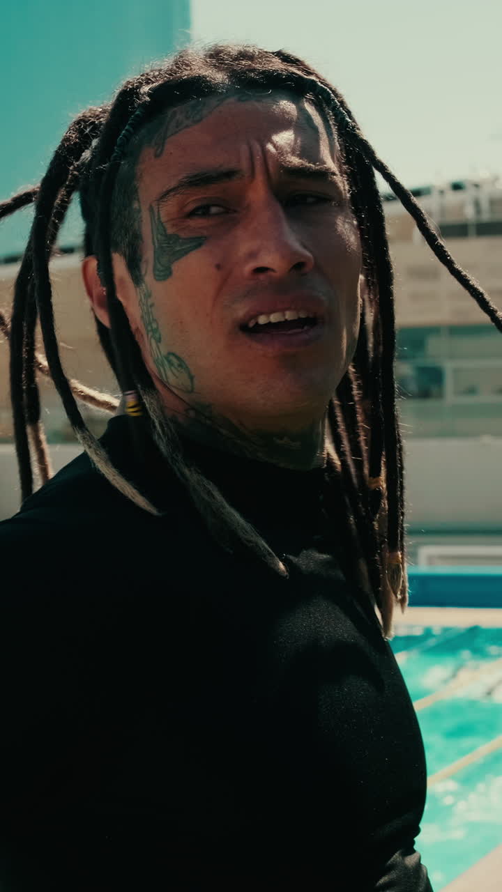 Primo piano di un uomo con dreadlocks e tatuaggi all'aperto