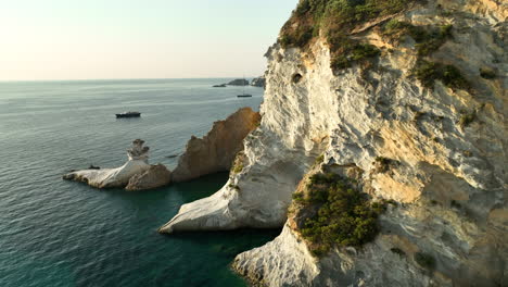 slow drone dolly shot of steep cliff walls illuminated by the warm rising morning sun at isola di ponza