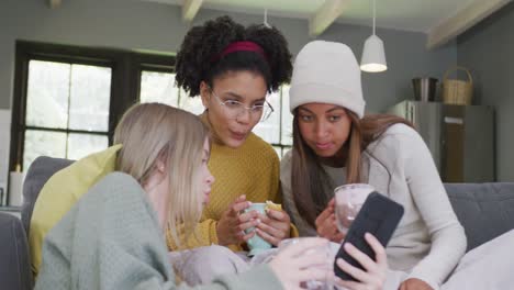 happy diverse teenager girls friends drinking coffee and using smartphone at home, slow motion