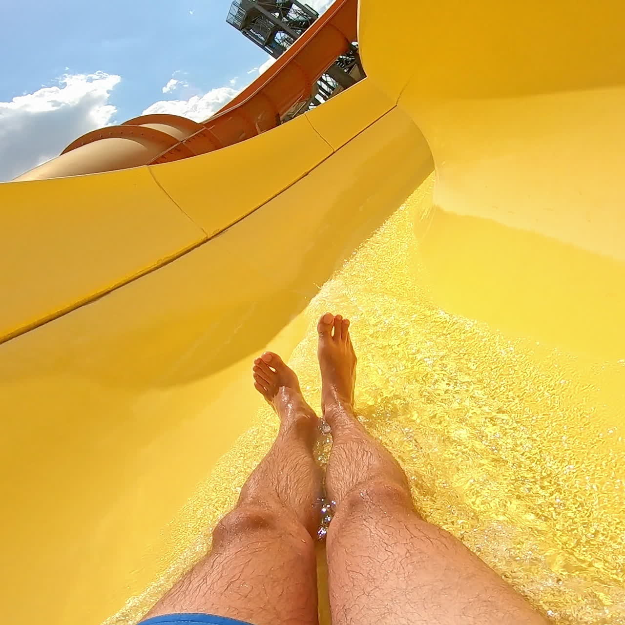 Fun down the water slide in summer day. Man goes down from water slide to swimming pool in aqua park. Quick way inside the pipe.