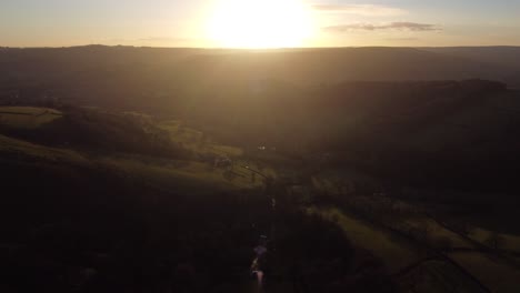 Views-over-the-Peak-District-as-the-sun-goes-down,-creating-a-haze-and-silhouettes-on-the-land