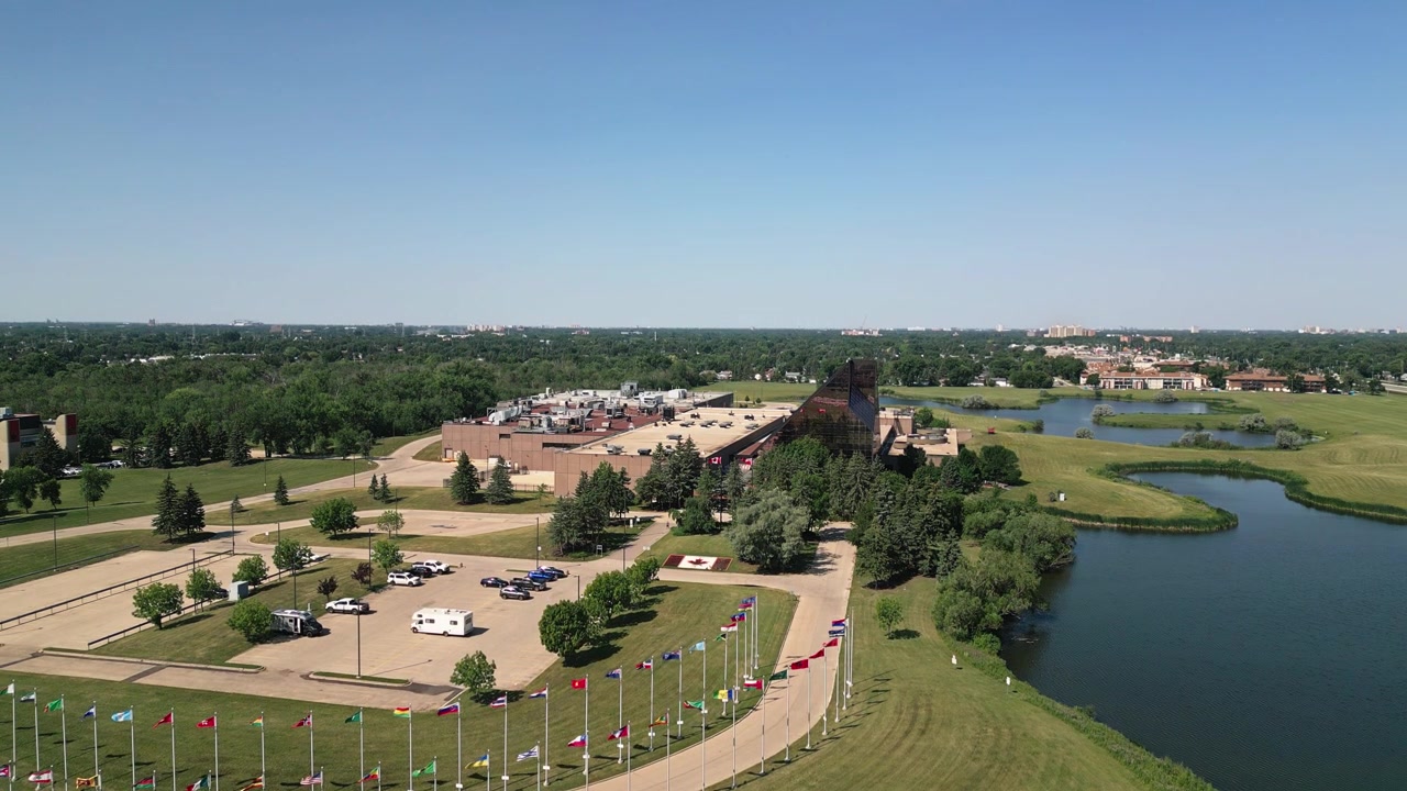 Ripresa aerea con drone in lenta ascesa che rivela la Zecca Reale Canadese e lo skyline di Winnipeg all'orizzonte durante una luminosa giornata estiva