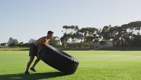 Fit-shirtless-caucasian-man-exercising-outdoors-with-tire