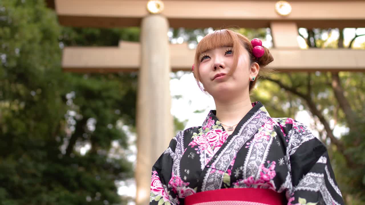 Giovane donna giapponese in kimono in piedi accanto a un Torii