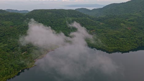 clouds and mist over lake da nao in ormoc, leyte philippines surrounded by forest and mountains, aerial view