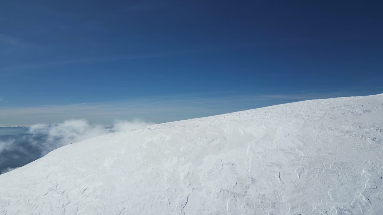 イタリア、モンテ・ヴェットーレ山頂からのドローン空撮映像：明るい冬の太陽、深い雪、そして山頂の下に広がる劇的な雲海。アルパイン、自然、シネマティックなプロジェクトに最適です。