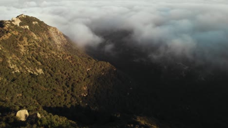 an aerial shot of the topanga canyon in malibu in california moving through the dense hillside and clouds early in the morning as the sun rises