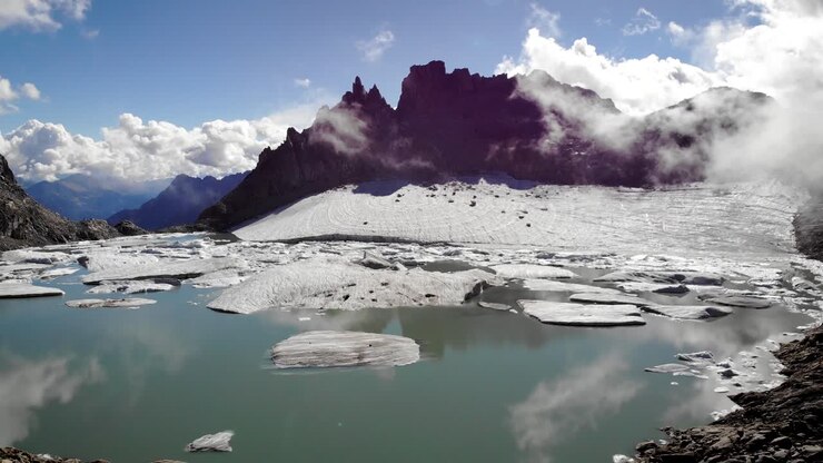 Aerial flyover from a glacier lake full of melted icebergs in remote parts of the Swiss Alps on a sunny day