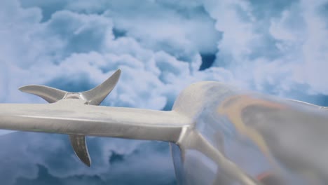 macro lens view of silver model airplane from the back at an angle with clouds in the background and video moving in