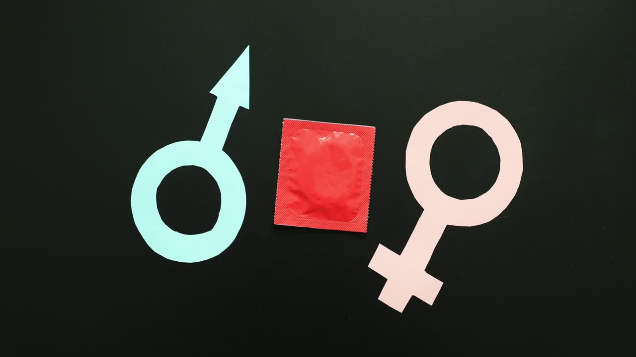 Mano femminile posa una confezione di preservativi su simboli maschili e femminili