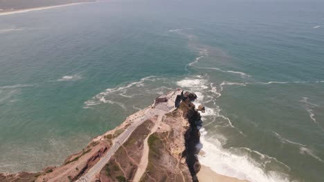 aerial high view seascape landmark lighthouse on cliffside, nazaré - portugal