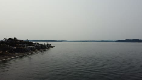 Drohnenaufnahme-Mit-Häusern-Auf-Dem-Wasser-Und-Einem-Großen-Schiff-In-Der-Ferne-Des-Puget-Sound