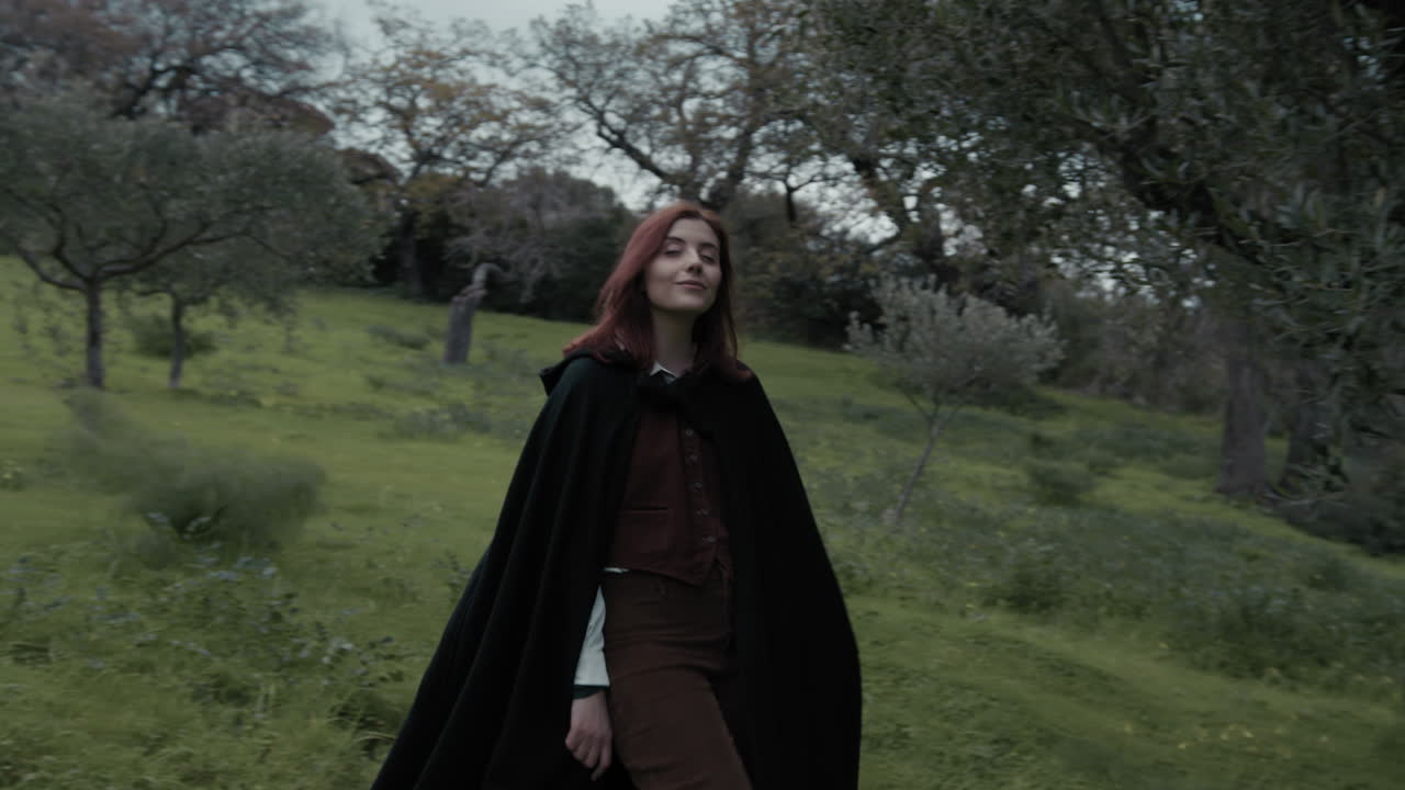 una joven misteriosa camina por el prado entre los olivos en una noche nublada.