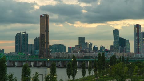 63 square building skyscraper sunset skyline and railway bridge subway train fast passing han river in seoul, south korea