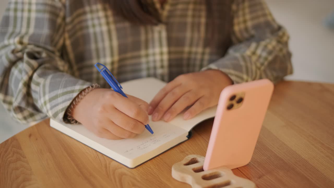 una mujer embarazada sentada en una mesa de madera en un interior acogedor y suavemente iluminado, escribiendo o escribiendo en un diario. la escena exuda calma, enfoque y una sensación de preparación durante la maternidad