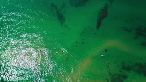 aerial-view-of-ocean,-crushing-waves,-surfers-and-beach,-4k