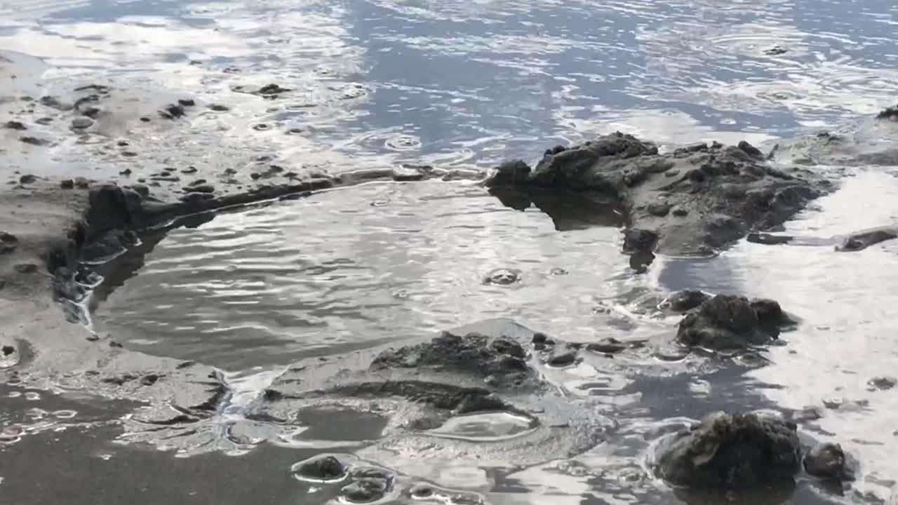 Acqua di mare che scorre dolcemente in una buca nella sabbia sulla spiaggia