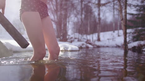 scandinavian woman steaming hot from sauna plunge into river in snowy woods