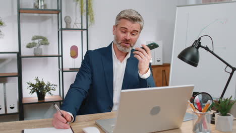 mature business man working, having mobile phone talk at office workplace using messenger chat apps