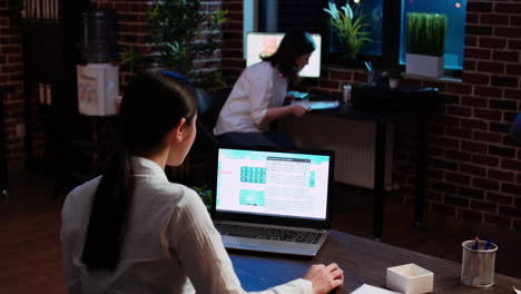 worker looking over statistical data financial graphs on laptop screen