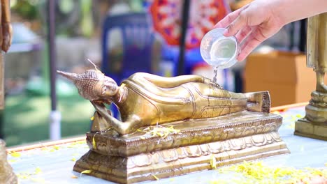 ritual of pouring water over a buddha statue