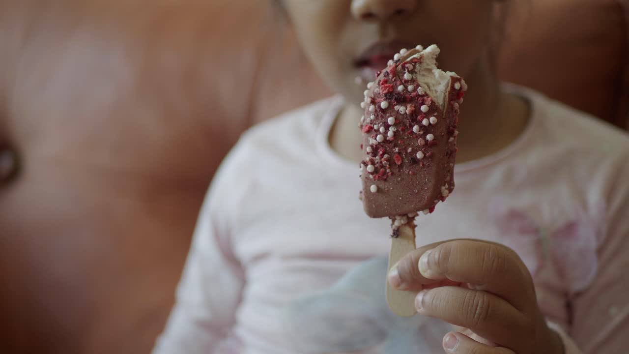 niña pequeña disfrutando de un helado de chocolate con salpicaduras