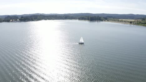 Drone-shot-of-a-sailboat-turning-around-in-a-lake-at-late-afternoon