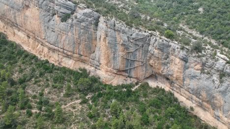 aerial views of the mont-rebei canyon with the cliffs, stairs on the walls, the lake, and the path along the canyon