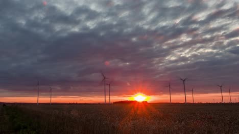 zoom in timelapse of a colorful sunset over a windmill farm