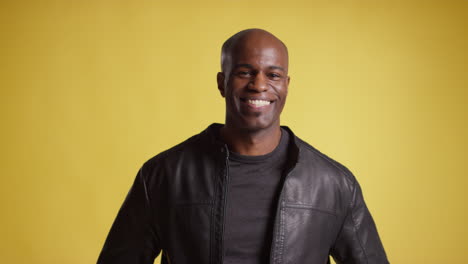 head and shoulders studio portrait of smiling and laughing mature man against yellow background 6