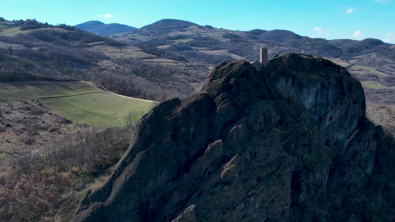 imágenes aéreas de pietra perduca, roca volcánica, iglesia situada en la piedra superior inmersa en el paisaje rural, tierra cultivada en val trebbia bobbio, emilia romagna, italia