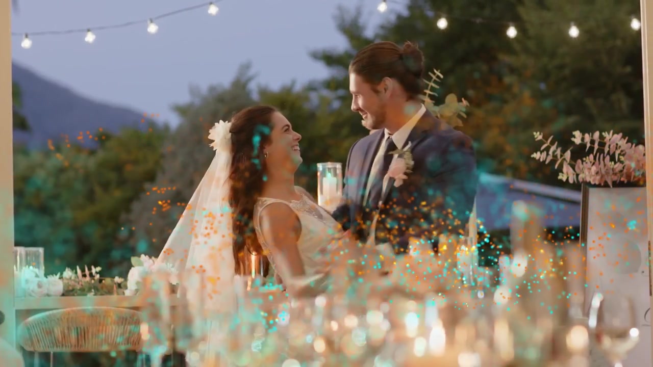 Lo sposo che conduce la sposa via dal tavolo, piroettando e chinandosi, mentre scintille color verde acqua si sovrappongono alla coppia per il matrimonio.
