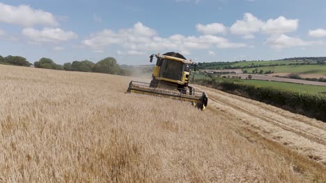 aerial view of a farmer driving a combine harvester up a barley field, emphasizing the hands-on approach to grain harvesting