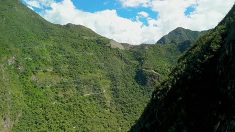 aerial ascend above forested slopes near machu picchu on sunny day in peruvian andes