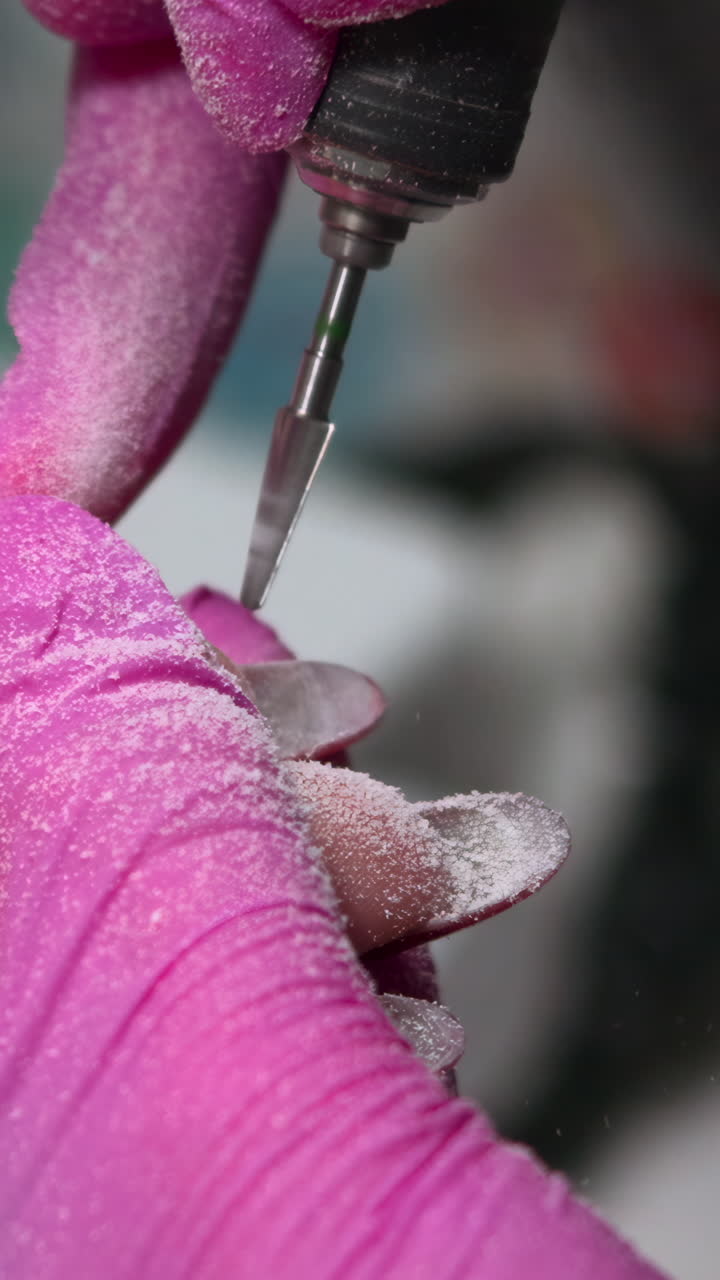 Nageltechnikerin entfernt Gelnagellack mit elektrischer Feile während einer Maniküre