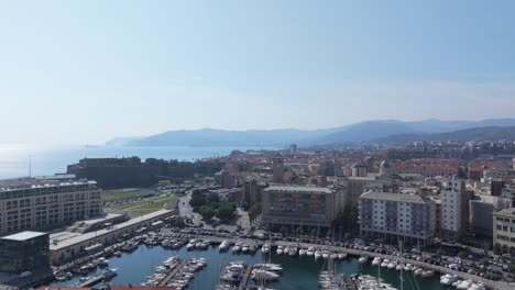 Harbor view of Savona, Italy, with boats, cityscape, mountains, and calm mood