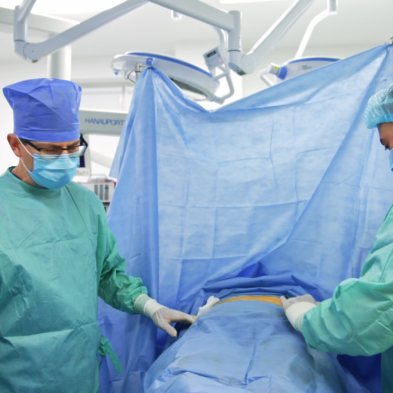 One of male surgeons takes a long needle out of patient's body and giving it to assistant. Stem cell operation in process at modern clinics