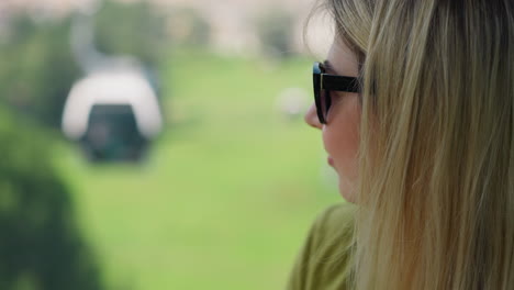 Thoughtful-woman-tourist-with-sunglasses-drives-cable-way