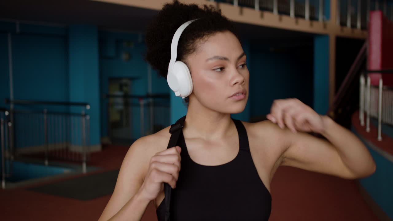 Afroamerican woman with headphones at the gym