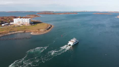 daytime drone view of a water shuttle getting underway on the harbor, pulling away from the dock