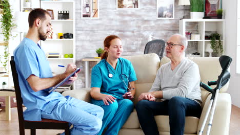 team of male and female nurses talking with an old and retired man